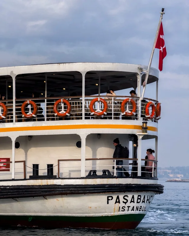 Bayrağı, turuncu can simitleri ve yolcularıyla Paşabahçe vapuru.